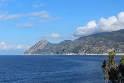 Scenic view of sea and mountains against blue sky