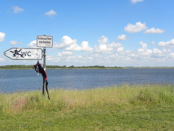 Information sign on field against sky