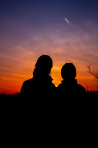 Silhouette couple against orange sky during sunset