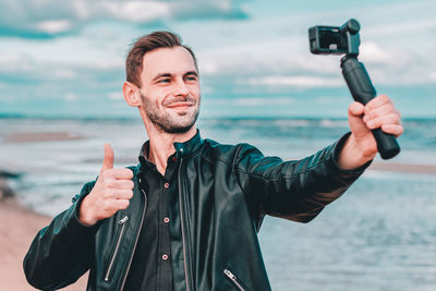 Man filming with video camera against sea