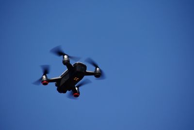 Low angle view of airplane flying against clear blue sky