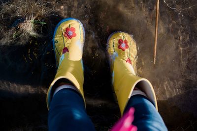 Childs feet in rain boots in a puddle of water and mud