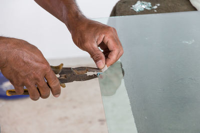 Close-up of man hands holding glass with pliers on table