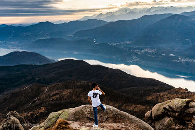 Rear view of man standing on mountain against sky