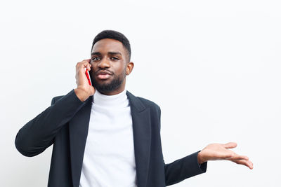 Portrait of businessman gesturing while standing against white background