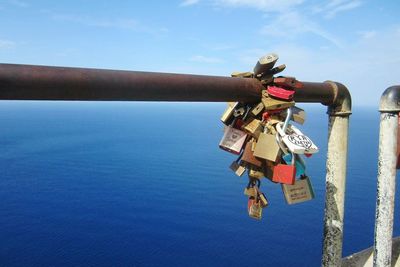 Love padlocks handing on railing against blue sea