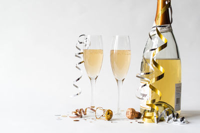 Two champagne glasses and bottle and against white background.