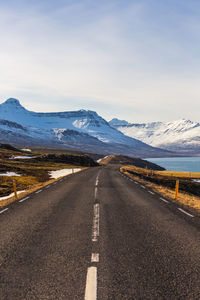 Road leading towards mountains against sky