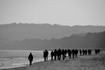 Silhouette people on shore against clear sky