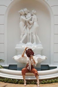 Midsection of woman with statue against building