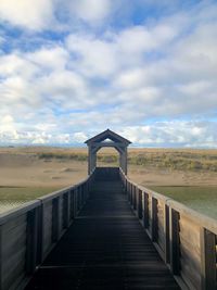 Wooden bridge over water against sky