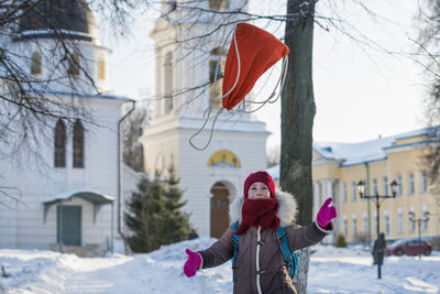 Girl throwing bag in mid-air while standing in snow