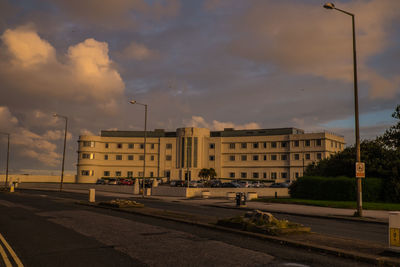 Street by buildings against sky during sunset