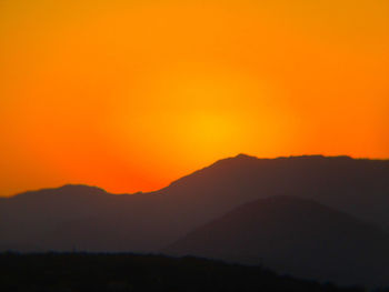 Scenic view of silhouette mountains against orange sky