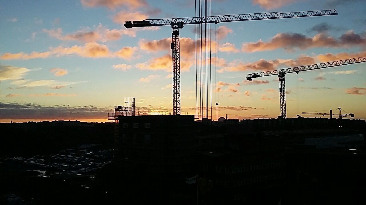 SILHOUETTE OF CRANES AGAINST SKY DURING SUNSET