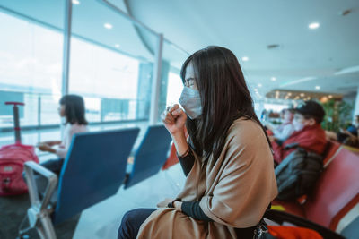 Side view of woman using mobile phone while sitting at airport