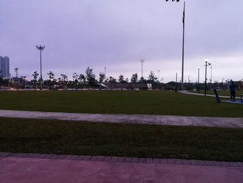 Street lights on field in city against sky