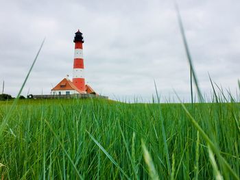 Lighthouse on field against sky