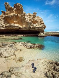 Rock formation on beach against sky