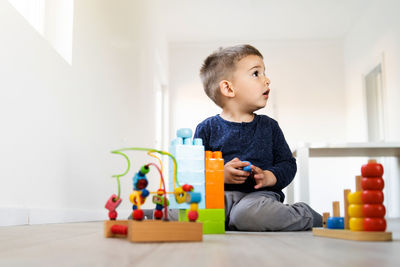 Cute boy looking away while sitting on sofa at home