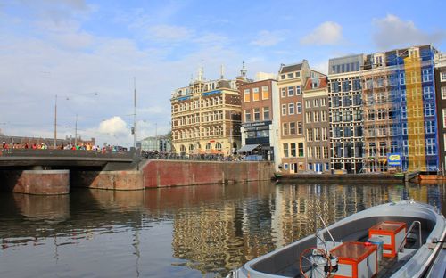 Boats moored on river by buildings in city against sky