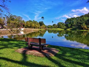 Bench by lake against sky