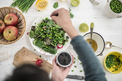 Hand preparing salad seasoning with black sesame