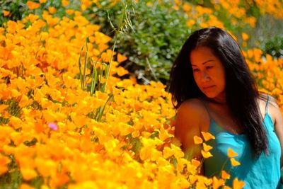 Close-up of woman with yellow flowers in sunlight