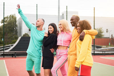 Friends standing on sports court against sky