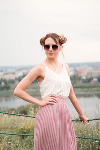 Portrait of young woman wearing sunglasses standing against clear sky