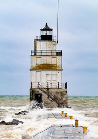 Lighthouse by sea against sky