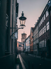 Street amidst buildings against sky at dusk