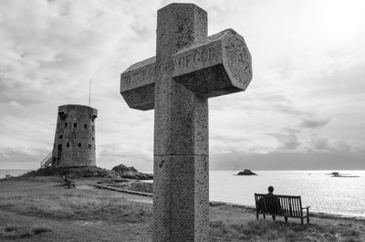 Cross on beach against sky