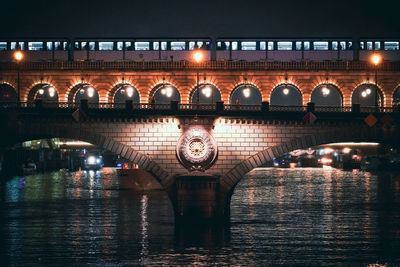 Illuminated bridge over river at night