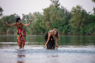 Woman with arms raised on lake against trees