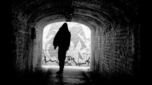 Rear view of people walking in tunnel