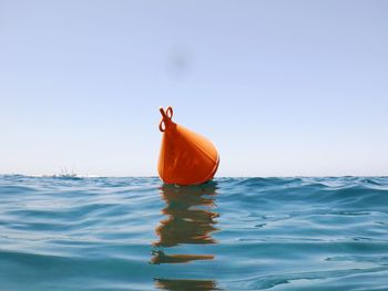 Person in sea by swimming pool against clear sky