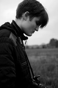 Side view of young man standing against sky