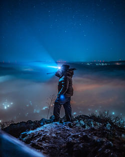 Man standing with illuminated light against sky at night