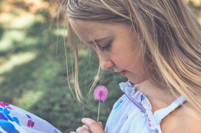 Close-up of girl holding dandelion on field