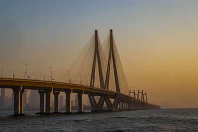 Bridge over sea against clear sky during sunset