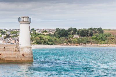 Lighthouse by sea against sky