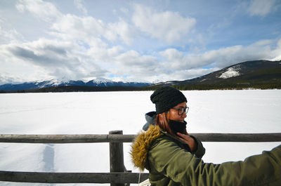 Smiling woman standing by railing snow covered mountain