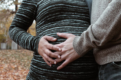 Couple holding hands over pregnant belly