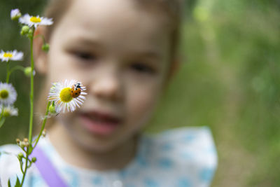 Close-up portrait of girl against white flowering plant