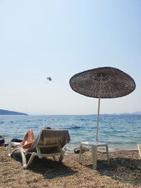 Chairs on beach by sea against clear sky