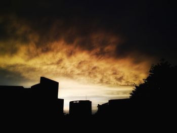 Low angle view of silhouette built structure against cloudy sky