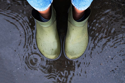 Woman wearing rubber boots standing in a puddle.