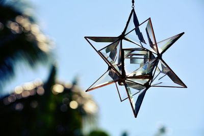 Low angle view of crystal suncatcher against blue sky and palm trees