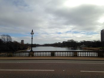 Road passing through city against cloudy sky